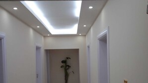 A hallway with white walls, a skylight, and a potted plant. - Ali Jasem Group (Doha)