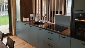 Een moderne keuken met een inbouwoven, een koffiezetapparaat en een spoelbak.
