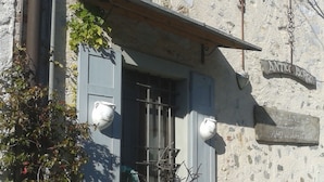 Un bâtiment à la façade en pierre, une fenêtre avec des volets, une enseigne indiquant « ANTICO BORGO », et un petit balcon orné de plantes.