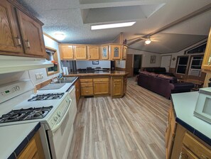 Una cocina compacta con armarios de madera, una estufa blanca y una zona de comedor con un sofá.