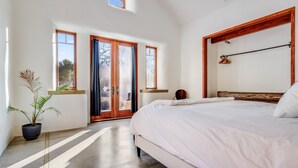 A modern bedroom with a large bed, a potted plant, and a view through the door. - Harmony Over The Hill (Templeton)