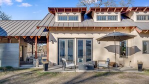 A modern house with a covered patio, large windows, and outdoor furniture. - Harmony Over The Hill (Templeton)