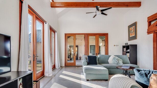 A spacious living room with a large sofa, a television, and a ceiling fan. - Harmony Over The Hill (Templeton)