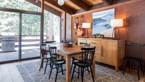 A wooden dining area with a large table, chairs, and a painting on the wall.