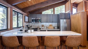 A modern kitchen with a large island, stainless steel appliances, and wooden accents.