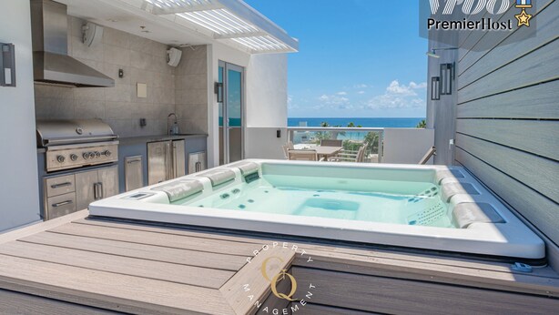 Una cocina moderna al aire libre con un jacuzzi, con vistas a una piscina y al océano.