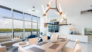 Una sala de estar moderna con una gran mesa de comedor, asientos cómodos y vista al agua.