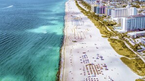 Vista aérea de una ciudad costera con una playa extensa, numerosos hoteles y una vista despejada del océano.