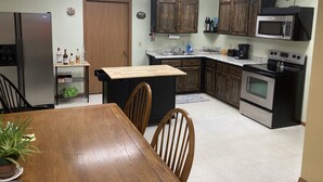 A kitchen with wooden cabinets, a refrigerator, a microwave, an oven, and a dining table with chairs. - Lodging in the heart of the Glacial Lakes, Waubay, Webster, Waubay Lake
 (Summit)