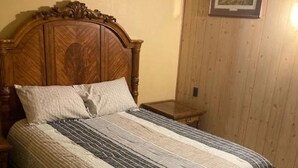 A bedroom with a wooden headboard, a bed with striped bedding, a nightstand, and a framed picture on the wall. - Lodging in the heart of the Glacial Lakes, Waubay, Webster, Waubay Lake
 (Summit)