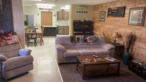 A living room with a sofa, armchair, coffee table, and a dining area with chairs and a table. - Lodging in the heart of the Glacial Lakes, Waubay, Webster, Waubay Lake
 (Summit)