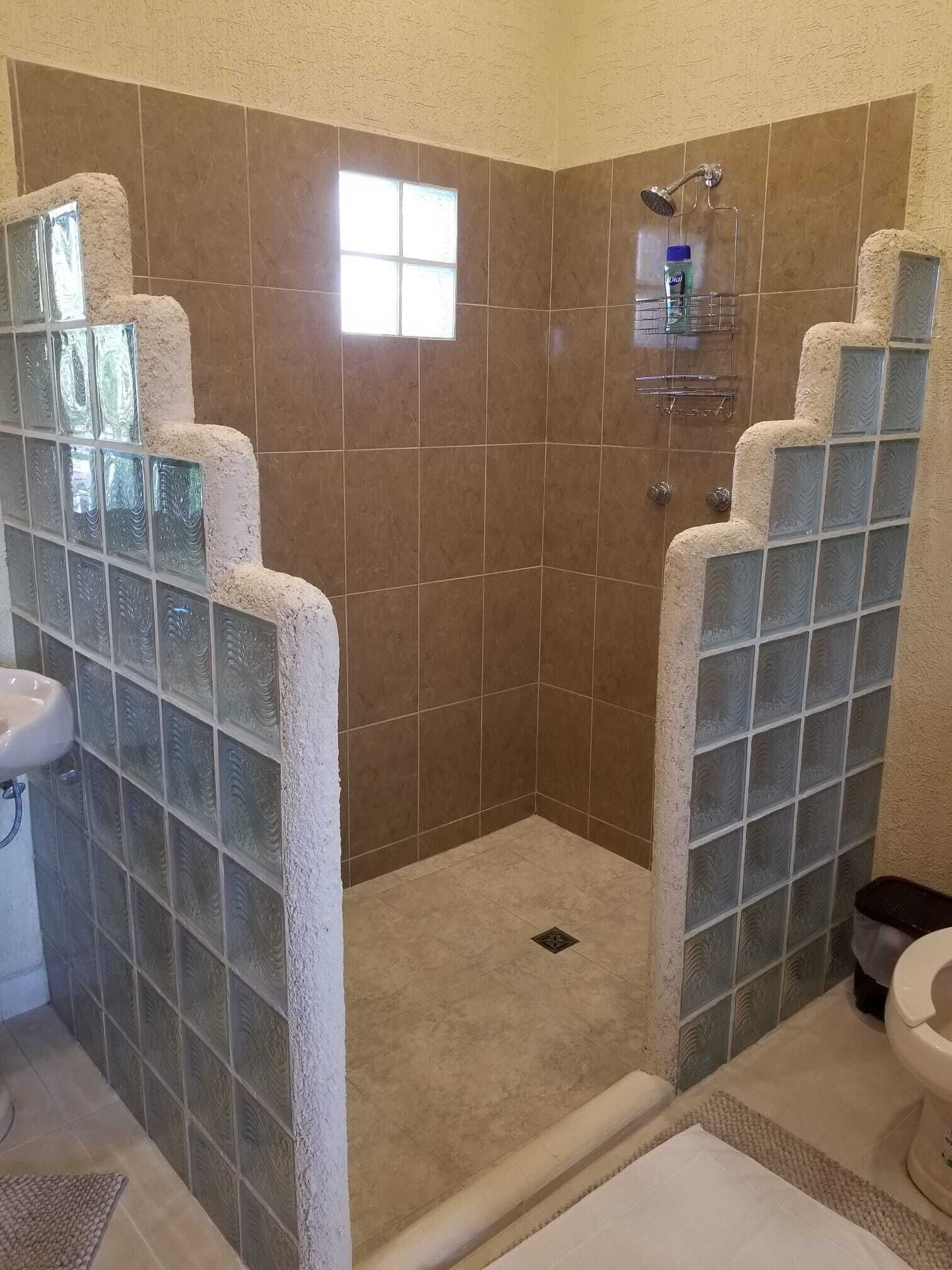 Ein Badezimmer mit Duschkabine aus Glas, einem Waschbecken und einer Toilette.