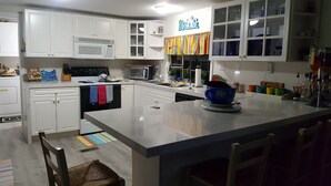 A modern kitchen with white cabinets, a central island, and a colorful window valance. - Key Largo heavenly retreat (Key Largo)