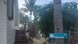 A residential area with a house, a gravel pathway, palm trees, and a sign indicating no working during drinking hours. - Key Largo heavenly retreat (Key Largo)