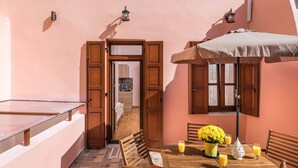 A cozy outdoor seating area with a wooden table, chairs, and a table umbrella. - Luxury king size studio with terrace at the heart of Chania old town (Chania)