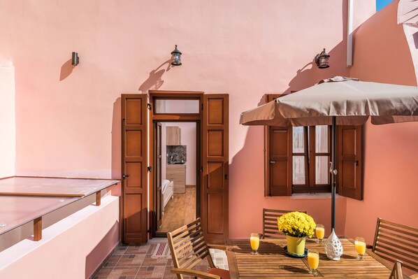 Un espace extérieur accueillant, aménagé avec une table en bois, des chaises et un parasol.