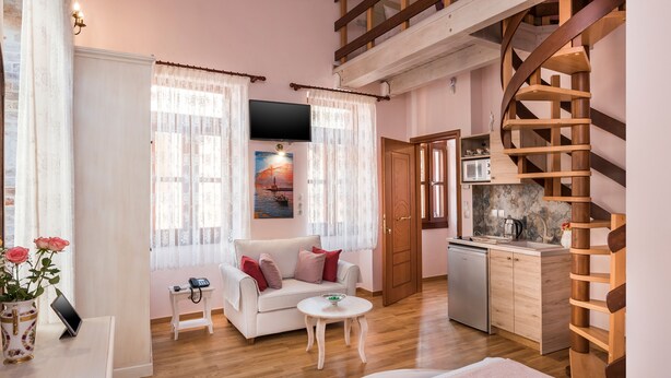 A cozy living room with a sofa, a small table, and a kitchen area with a sink and cabinets. - Luxury king size studio with terrace at the heart of Chania old town (Chania)