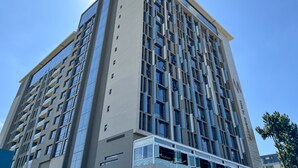 A tall, modern building with a symmetrical facade, large windows, and a prominent entrance at the base. - Sandton Smart Apartment Sixteen (Sandton)