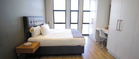 Une chambre moderne avec un grand lit, des tables de chevet, un bureau et une armoire.