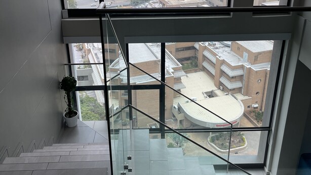 A high-rise building with multiple floors, large windows, and a view of the surrounding cityscape. - Sandton Smart Apartment Sixteen (Sandton)