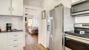 Une cuisine moderne avec des meubles blancs, des appareils en acier inoxydable et un plancher en bois.
