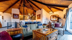 A spacious living room with a high ceiling, wooden beams, a sofa set, a coffee table, and a dining area with a kitchen in the background. - Slopeside Beech Mtn - Ski-In/Ski-Out - Beat the Heat - Biking + Mountain Views (Beech Mountain)