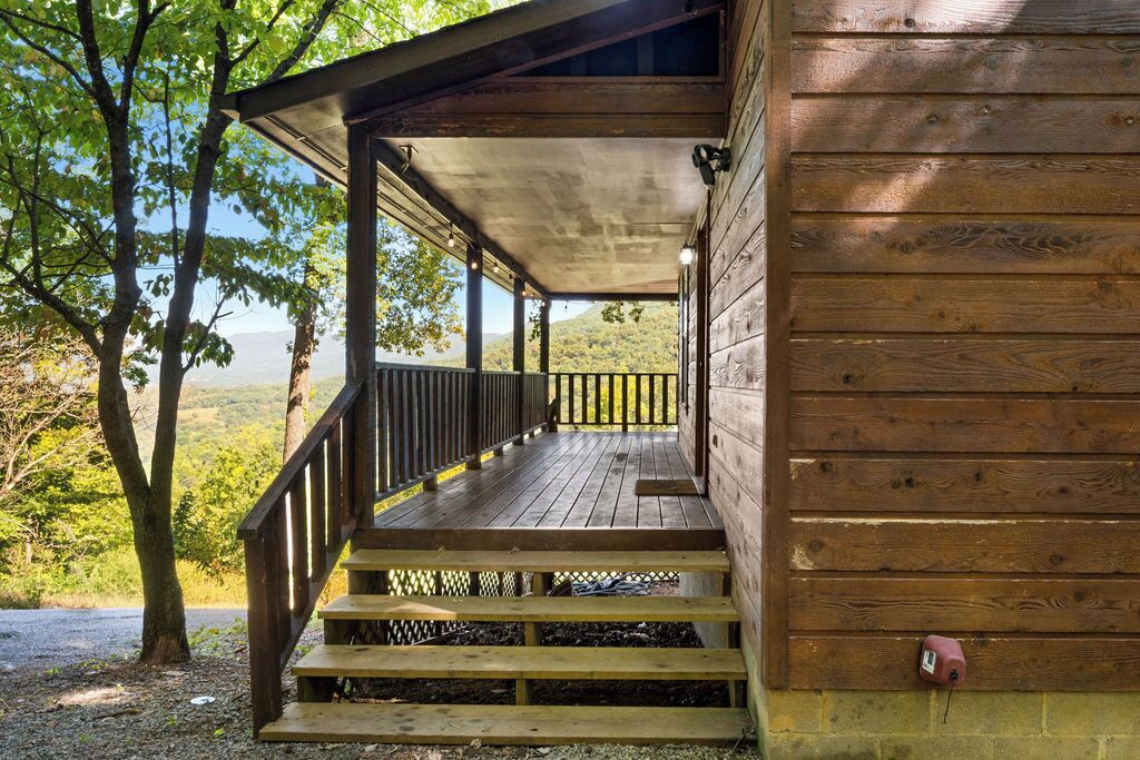 Eine Holzhütte mit einer Veranda und Treppen zu einem überdachten Bereich.