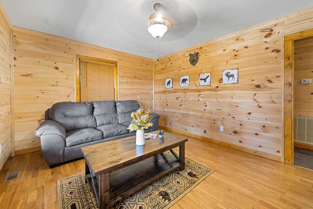 Ein gemütliches Zimmer mit einem grauen Sofa, einem Holztisch und einer Wand mit Tierdrucken.