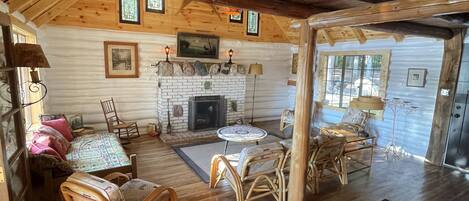 A rustic cabin interior with a fireplace, wooden furniture, and a dining area.