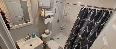 A bathroom with a sink, toilet, shower, and a towel rack.