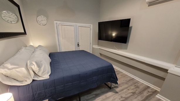 Ein Schlafzimmer mit einem Bett, zwei Uhren, einem Fernseher und einem Kleiderschrank.