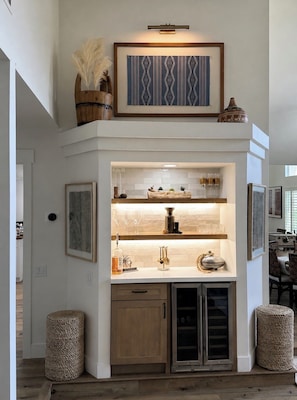 Una cocina moderna con una vinera empotrada, un jarrón decorativo y una obra de arte enmarcada sobre la encimera.