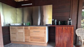 A kitchen with wooden cabinets, a countertop, and a backsplash. - Bungalow Temanea Pirae Tahiti (Papeete)