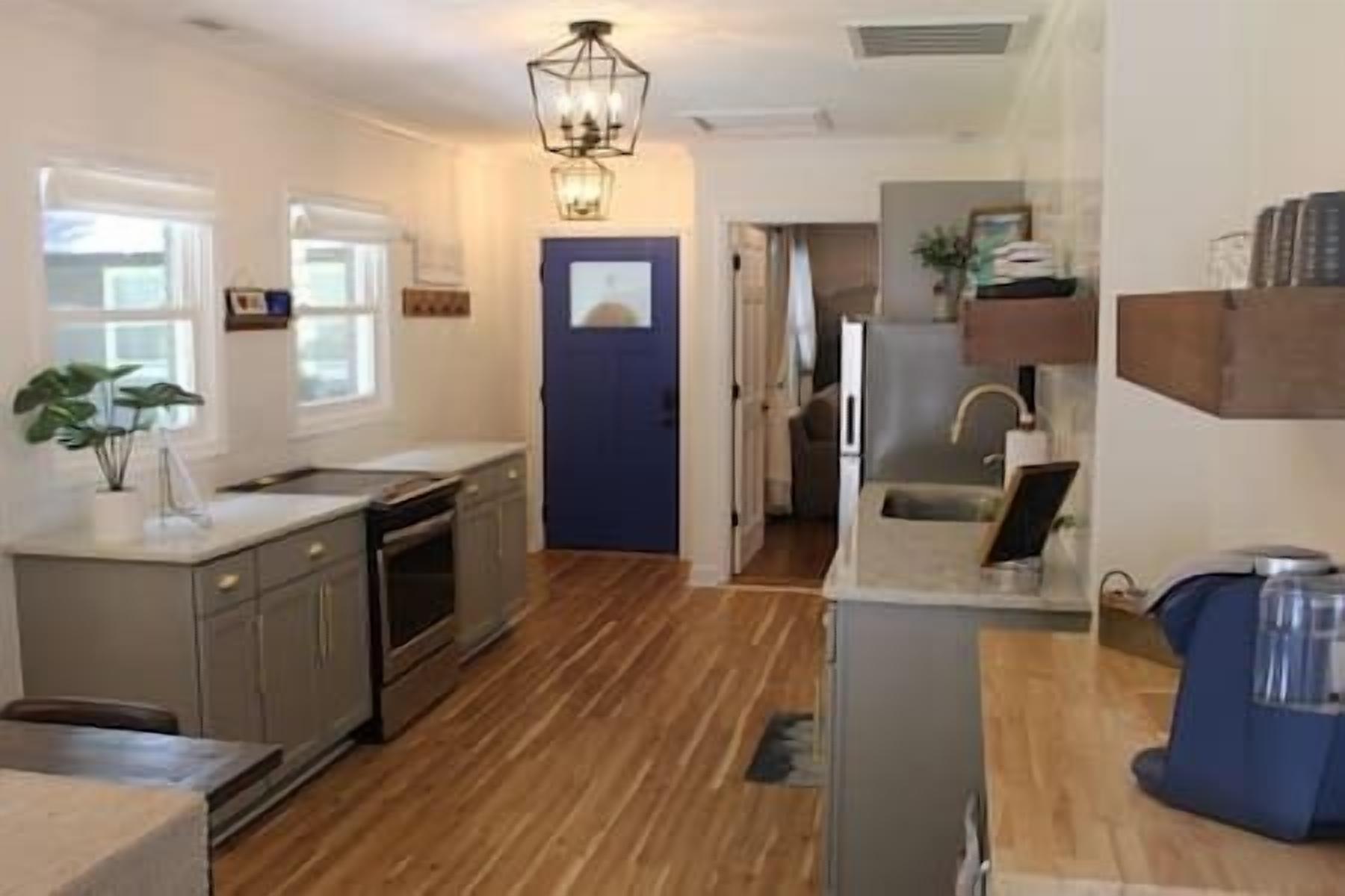 A kitchen with wooden flooring, a built-in oven, and a sink.