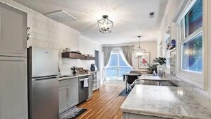 A modern kitchen with a central island, wooden flooring, and a view to the outside.