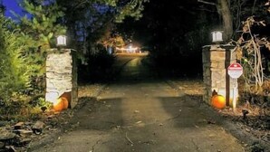 A gated entrance with stone pillars and a stop sign.