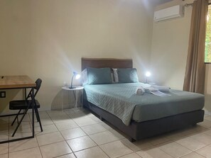 A bedroom with a bed, bedside tables, a desk, and a chair.