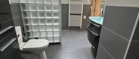 Une salle de bain moderne équipée de toilettes, d’un lavabo et d’un espace douche.