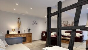 Ein modernes Wohnzimmer mit einem Bett, einem weißen Tisch, einer Holzkommode und einer großen Holzbalkenkonstruktion.