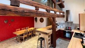 Eine moderne Küche mit Holzbalken, einem Essbereich mit roter Wand und einer Kücheninsel.