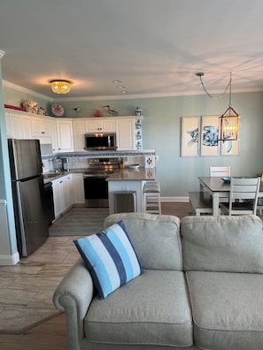A modern kitchen with white cabinets, stainless steel appliances, and a dining area with a table and chairs.