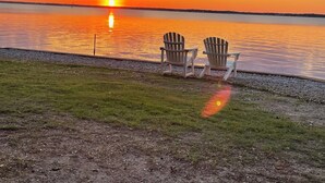 Two Adirondack chairs facing a sunset over a calm body of water. - Oceanfront - The Ocean Club - Sand, Sun & Family Fun - Indian Beach/Emerald Isle (Indian Beach)