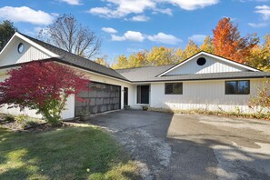 Une maison de plain-pied avec un garage, une allée et une pelouse bien entretenue.