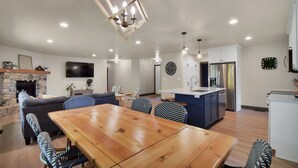 A spacious living area with a wooden dining table, blue patterned chairs, a stone fireplace, a flat-screen TV, and a kitchen with modern appliances. - 4 bedroom - 3 bath bike to downtown Sister Bay, Door County. (Sister Bay)