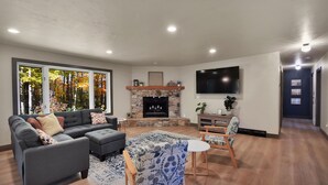 A modern living room with a sectional sofa, a fireplace, a flat-screen TV, and a dining area with a patterned tablecloth. - 4 bedroom - 3 bath bike to downtown Sister Bay, Door County. (Sister Bay)