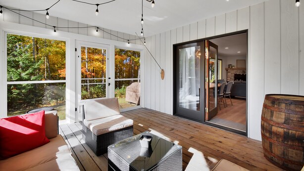 A modern outdoor living area with a wooden deck, a sofa, a table, and a barrel. - 4 bedroom - 3 bath bike to downtown Sister Bay, Door County. (Sister Bay)