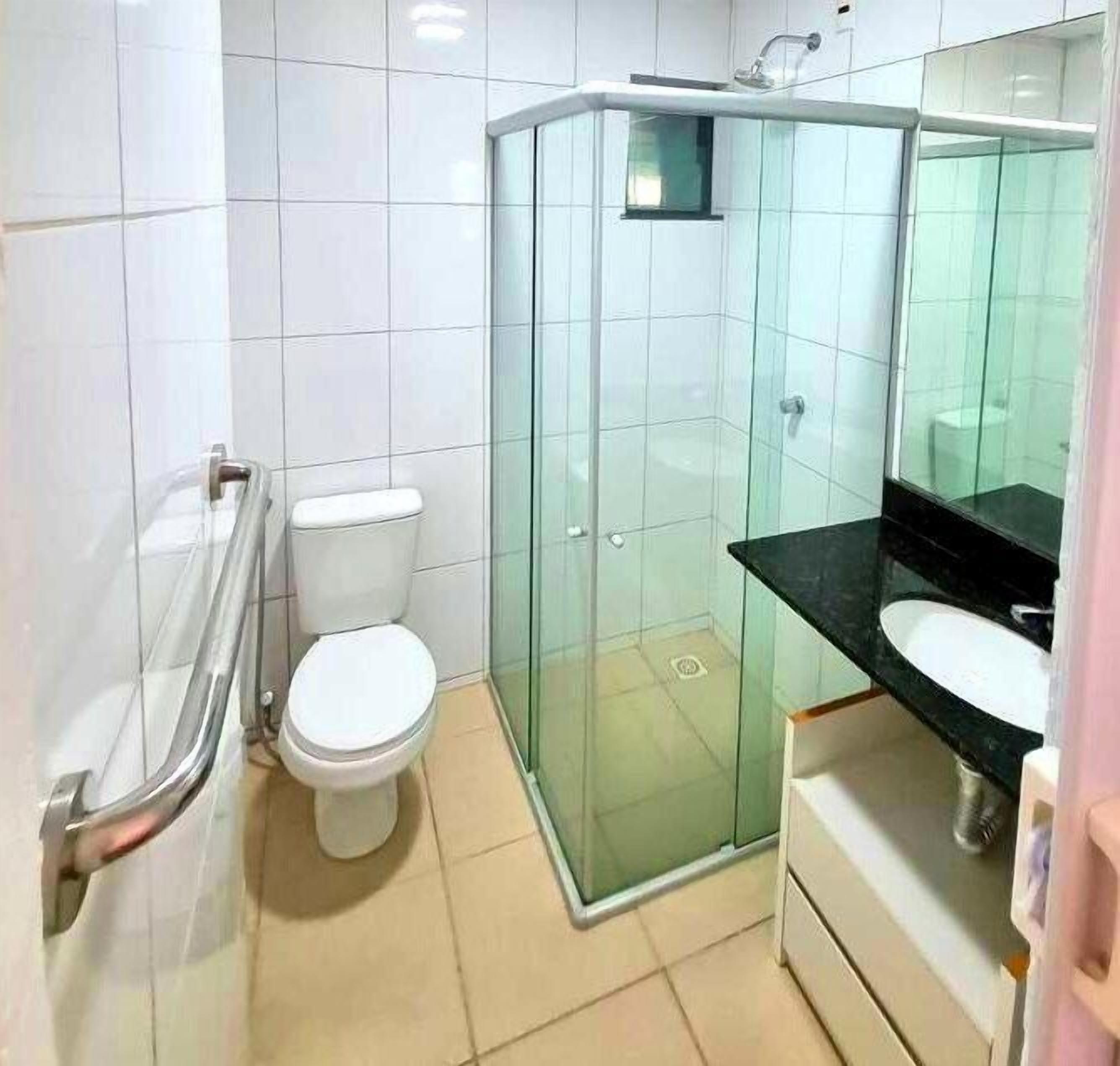 A modern bathroom with a glass shower enclosure, a white toilet, and a black sink.