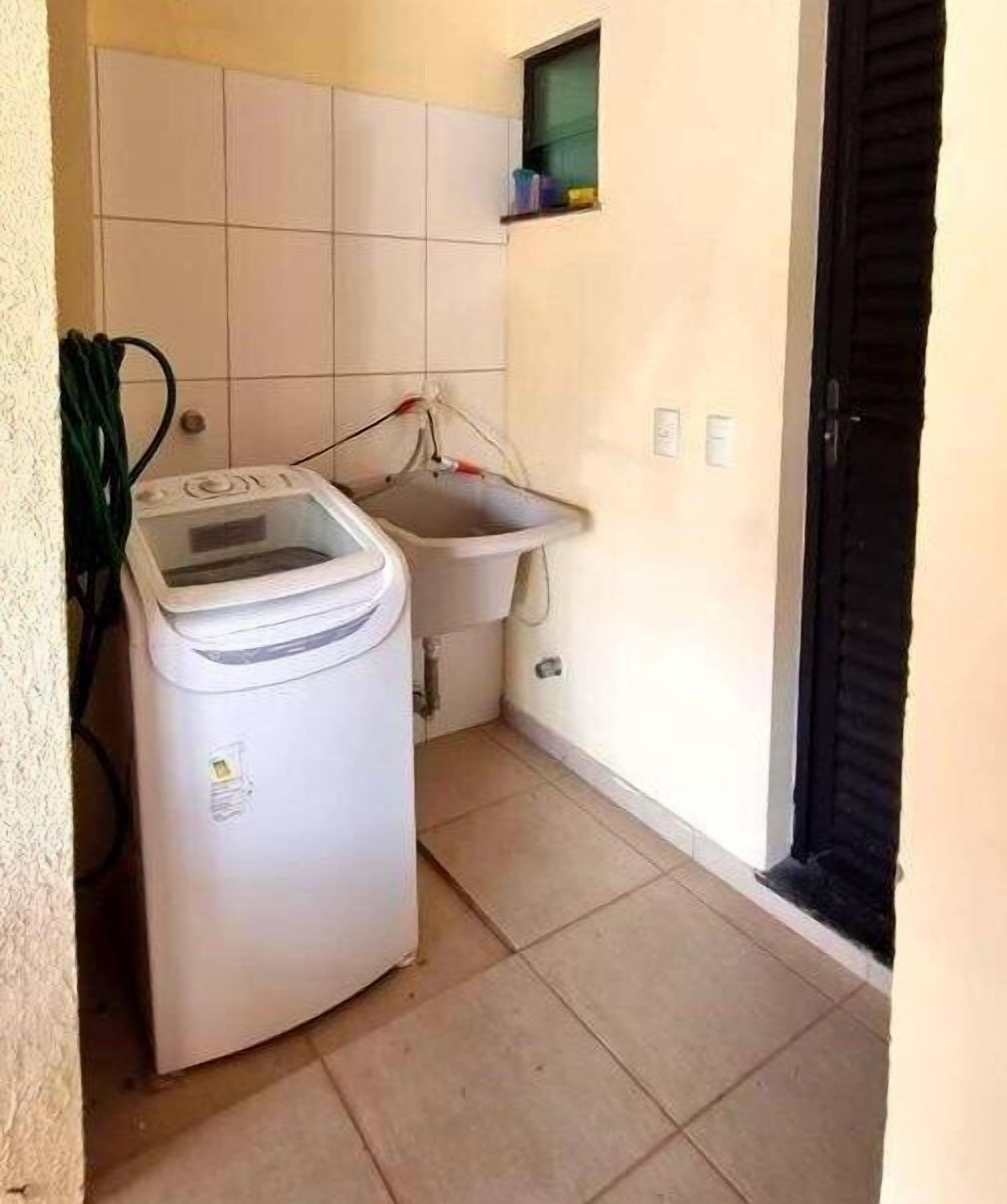 Una cocina pequeña y limpia con lavadora, pileta y paredes con cerámica.