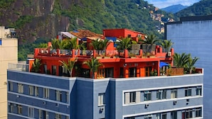 A multi-story building with balconies, surrounded by greenery and mountains. - The Coral Penthouse - 3 Bedrooms (Rio de Janeiro)
