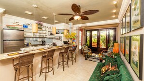 A modern kitchen with a central island, bar stools, and a dining area with a sofa and chairs. - The Coral Penthouse - 3 Bedrooms (Rio de Janeiro)